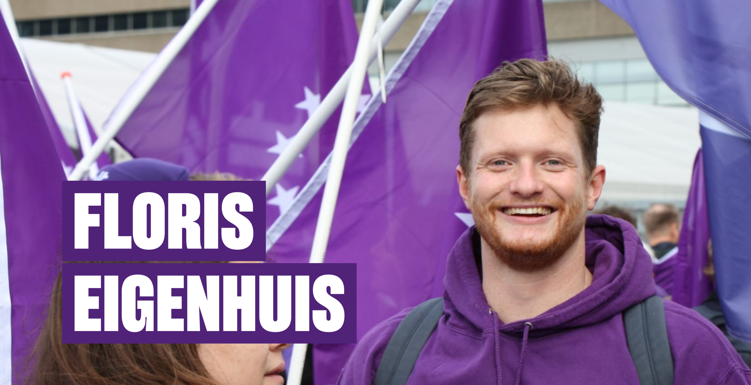 Floris Eigenhuis staat in het midden van een paarse menigte en kijkt lachend in de camera.